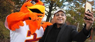 Man takes a selfie with the SU Mascot Benny The Hawk