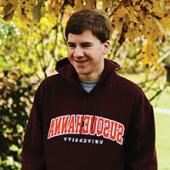 Young man standing in front of greenery, wearing a black Susquehanna sweatshirt